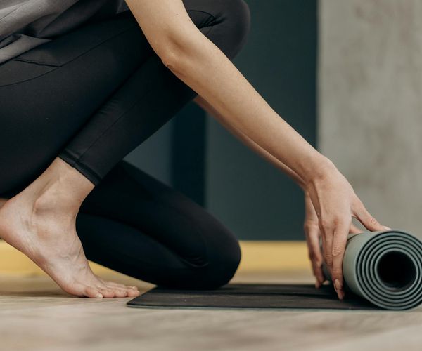 A person rolling out a yoga mat, preparing for a practice.