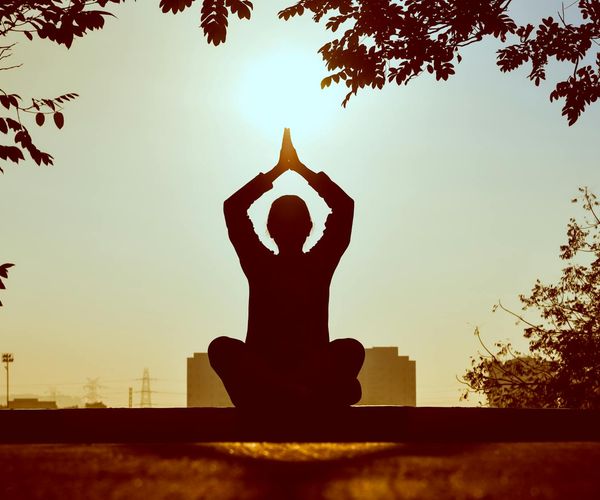 Silhouette of a person meditating during sunrise, symbolizing mindfulness.